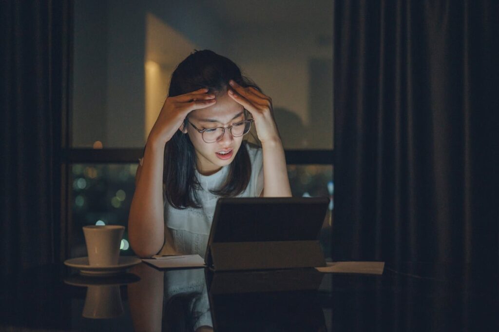 Concerned young person with head in hands gazing at a screen.