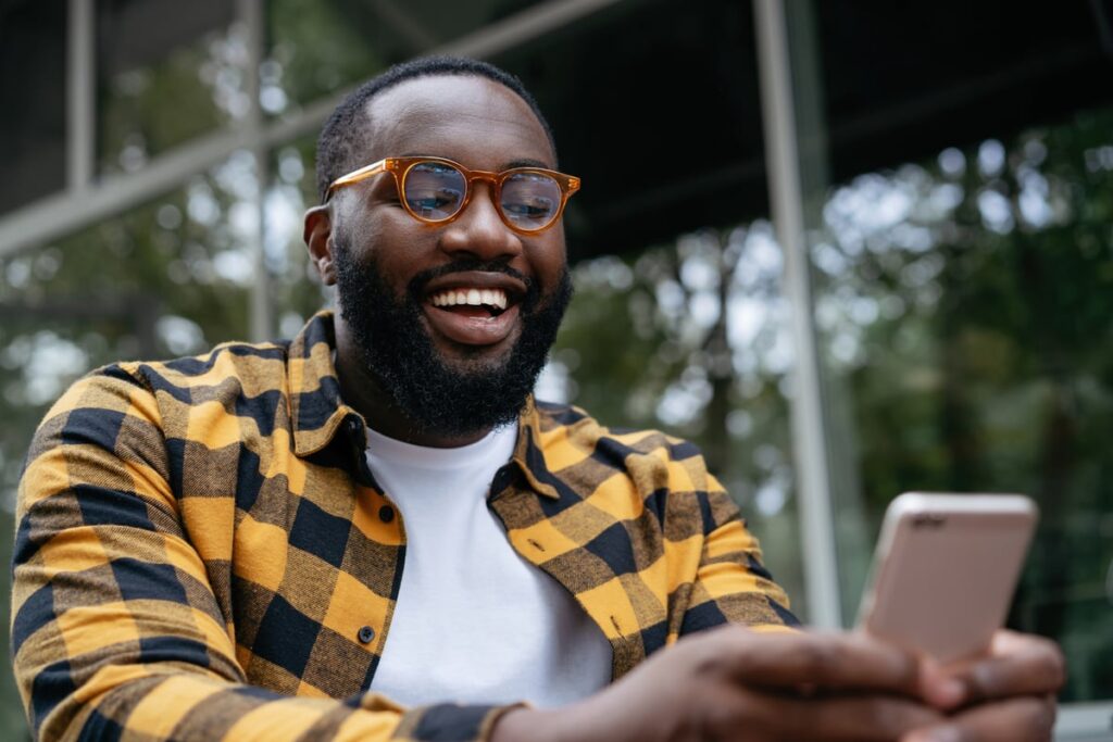 A smiling person looking at a phone