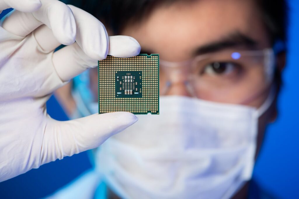 Person in specs holding an integrated circuit.