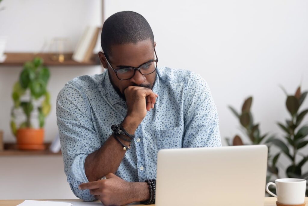 A worried person is staring at a laptop screen.