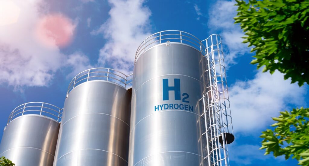 Hydrogen tanks among a blue sky and green leaves.