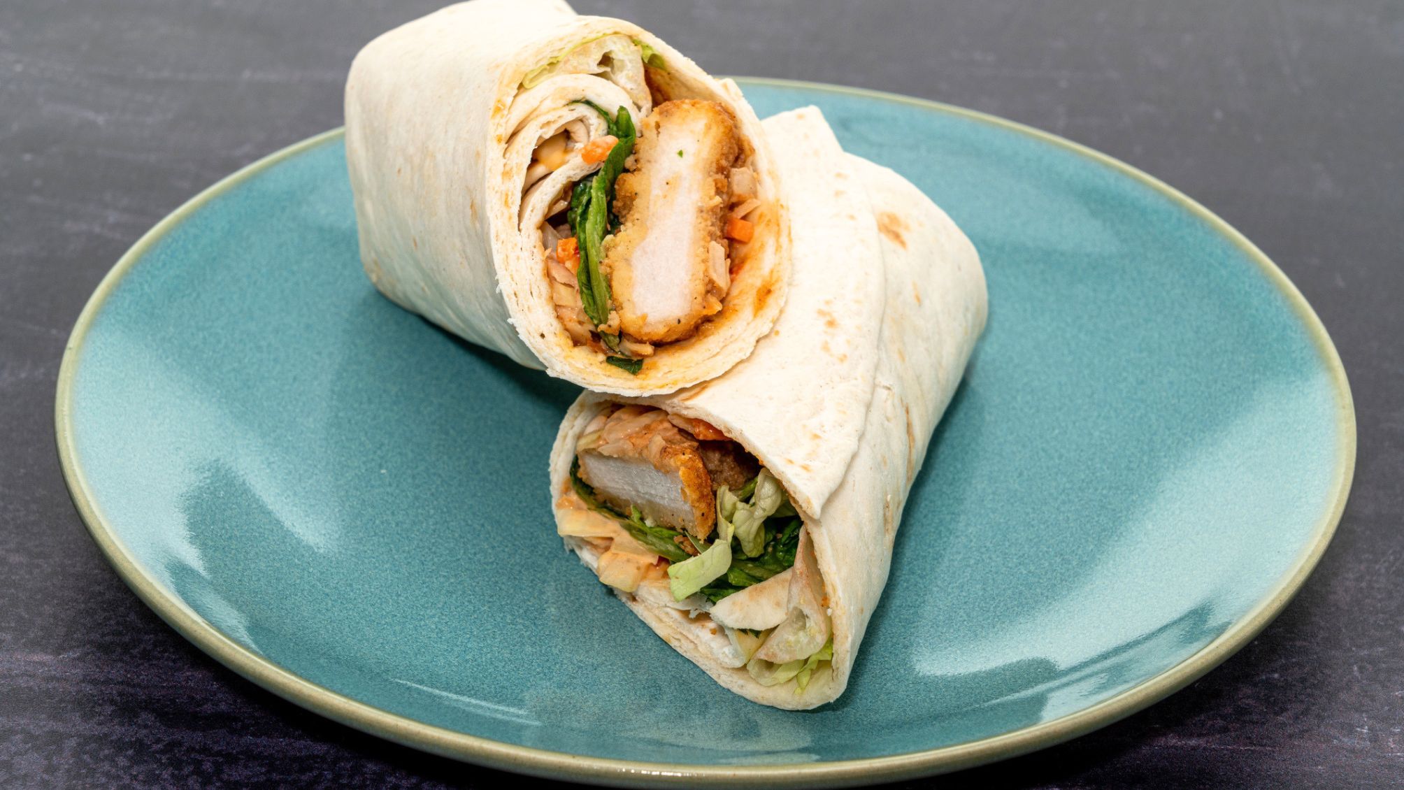 A chicken wrap on a turquoise plate.