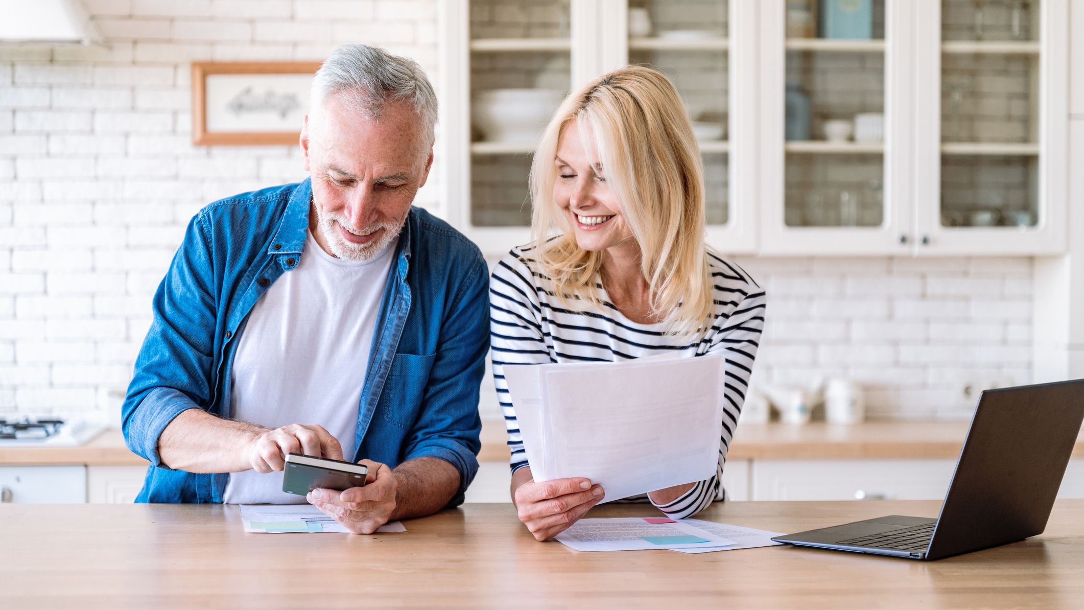 A couple managing their household budget together next to a laptop