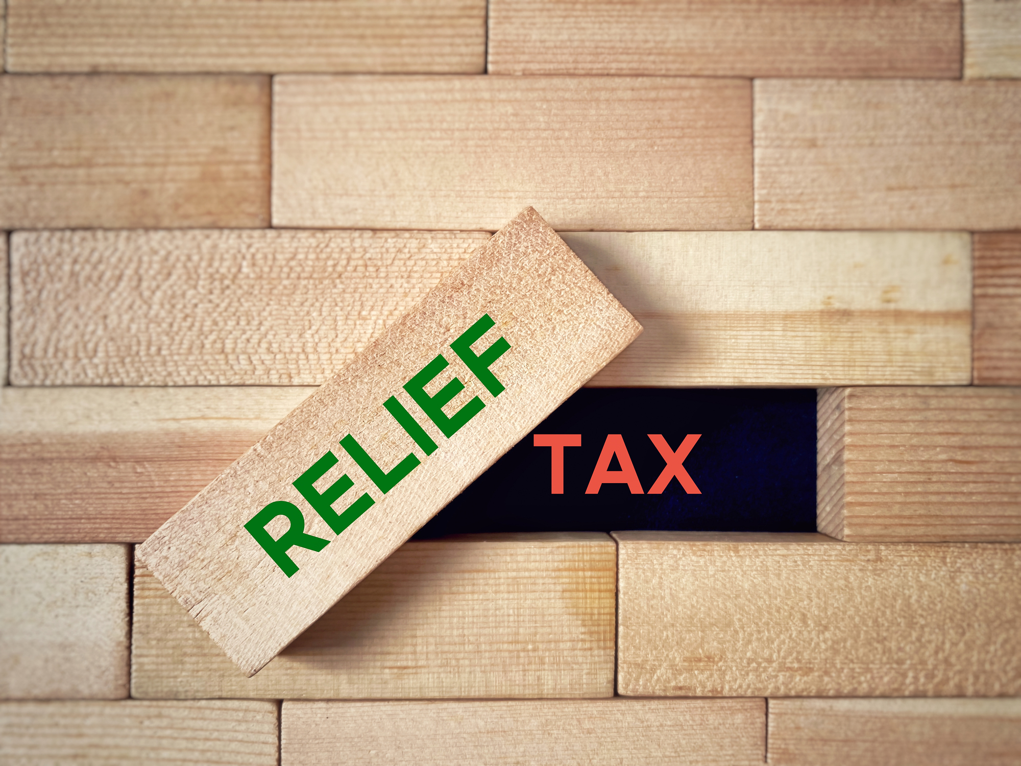 wooden block pattern, with a removed block that says "relief" and the underlying space spelling out "tax"