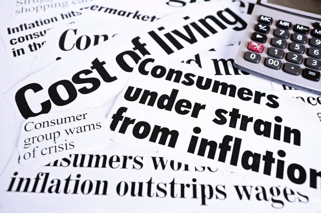 A calculator placed next to several newspaper clippings highlighting rapidly rising prices.