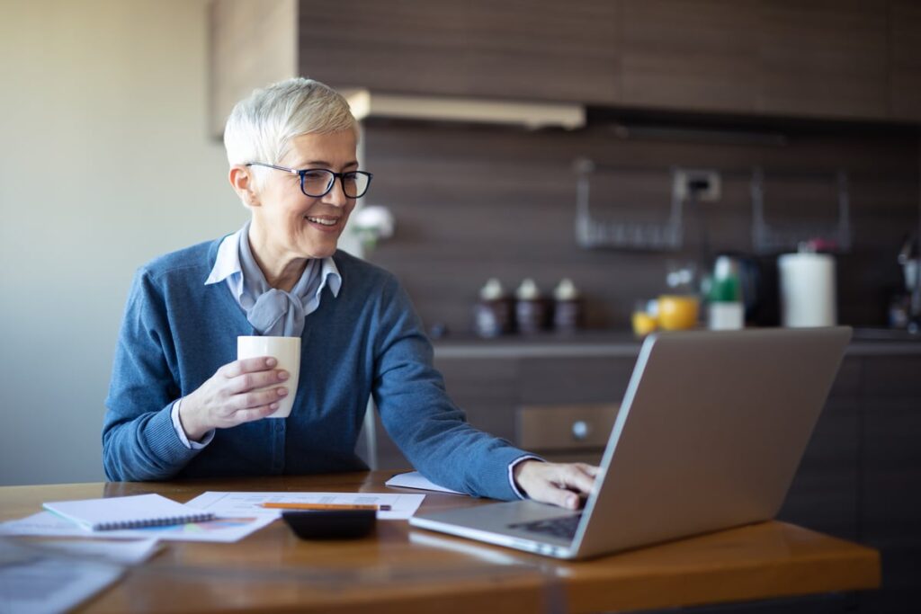 An investor seated at a table is using a laptop.