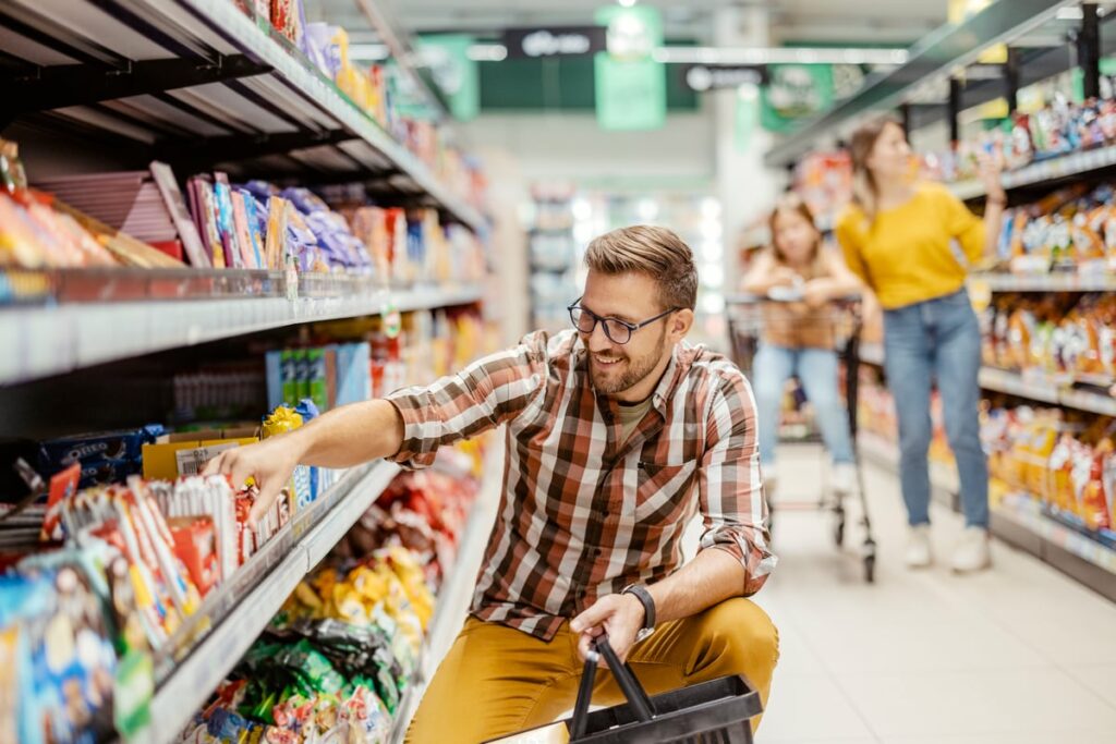 Shoppers in a grocery store's candy and snacks aisle.