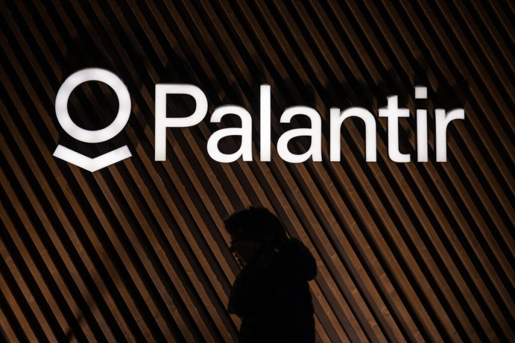 Palantir logo on the wall above the shadow of a person walking by.