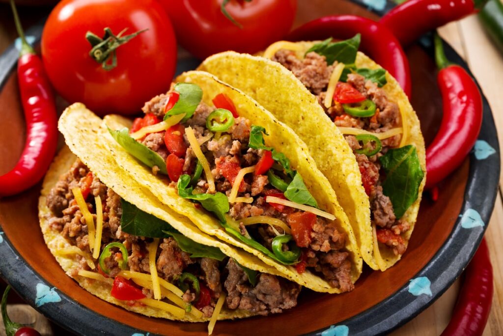 Three tacos sitting on a red plate.