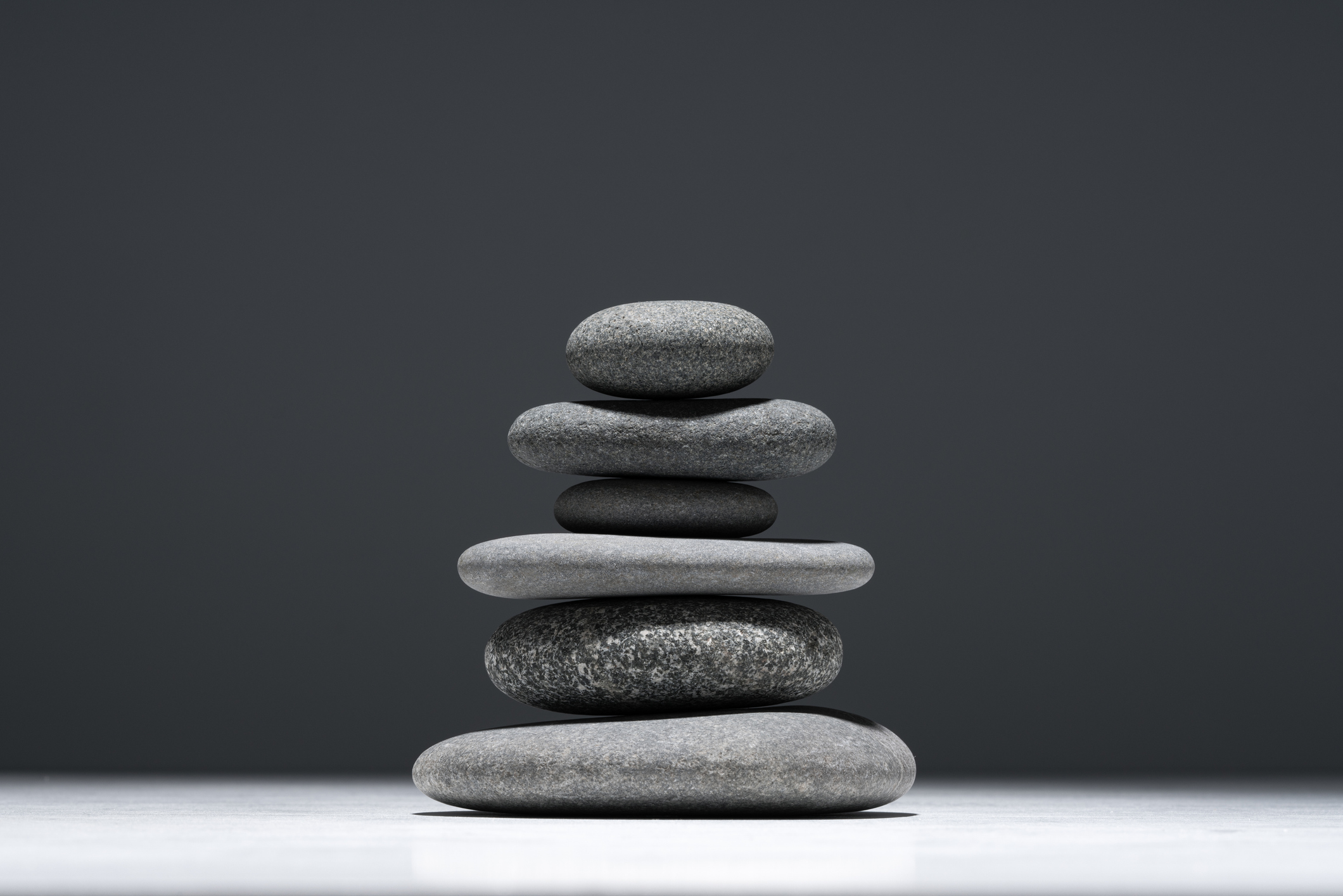Stack of Balanced Pebbles Against Gray Colored Background.