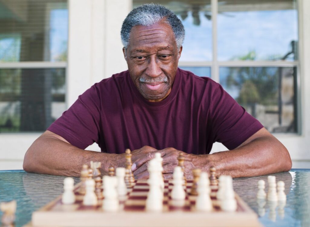 A person sitting in front of a chess board contemplating game strategy.