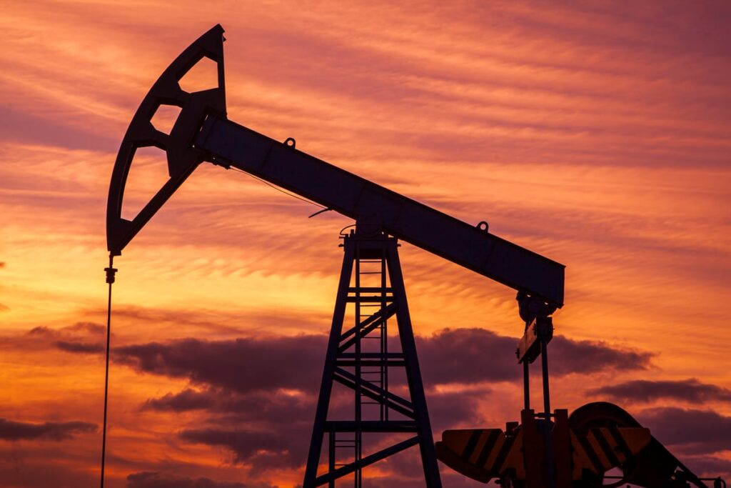 An oil rig is operating under a red sky.