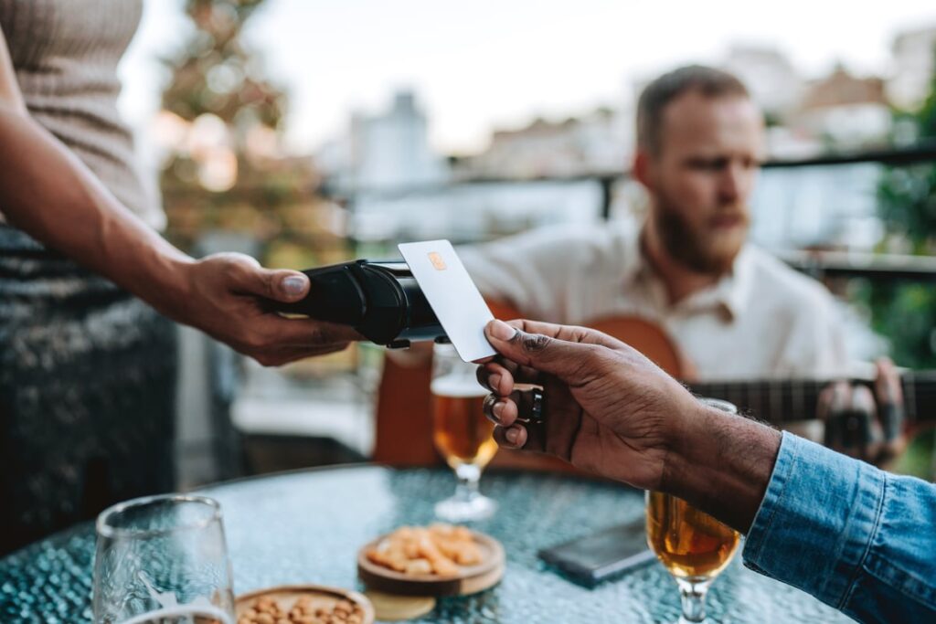 Person paying for a restaurant meal with a payment card.