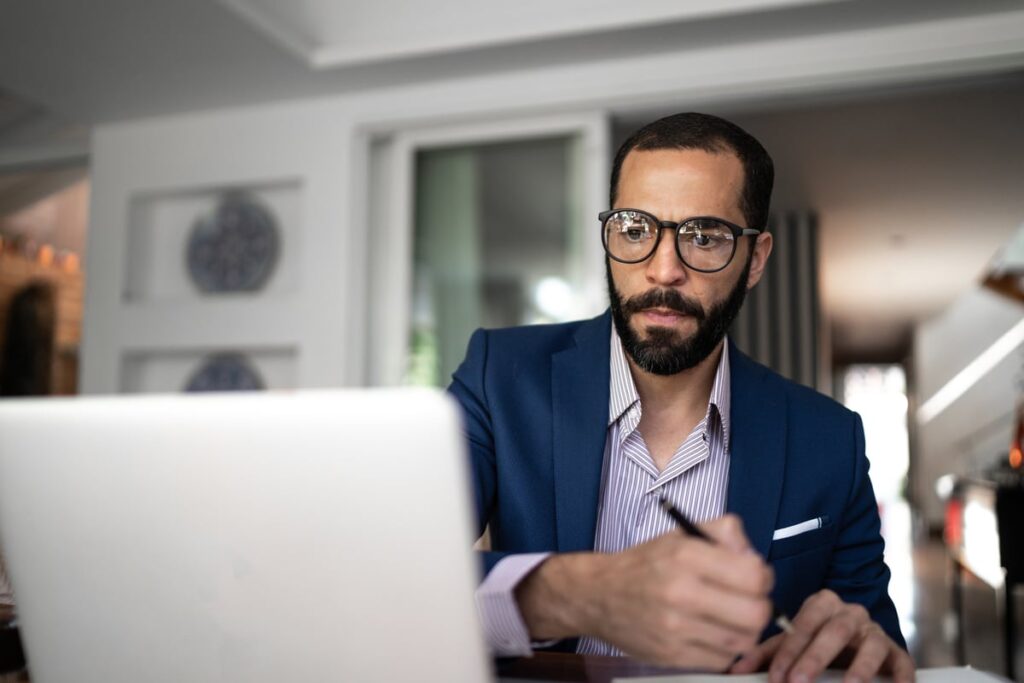 Person looking at a laptop and writing a note.
