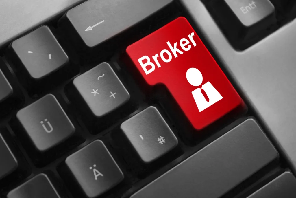 A close-up of a computer keyboard with a large red key labeled Broker and a white icon of a person in a suit, replacing the usual Enter key. The surrounding keys have black backgrounds with white symbols.