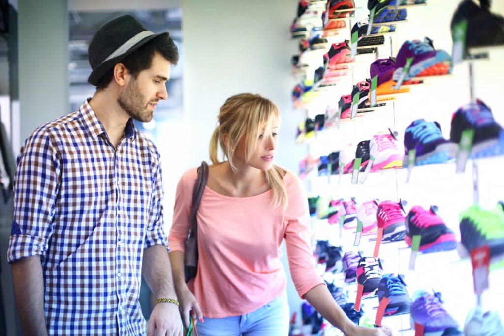 A couple shops for sneakers at a shoe store.