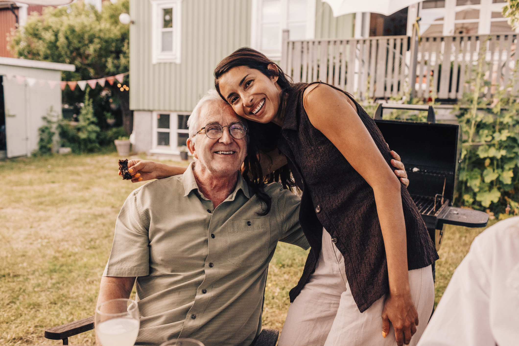 Portrait of smiling woman embracing father at back yard birthday party