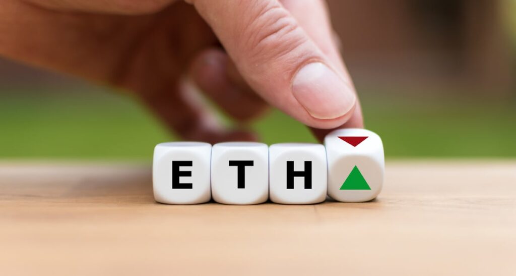 The word ETH is spelled out on three dice, and a hand switches a fourth die to rest between a green and a red arrow on its surface.