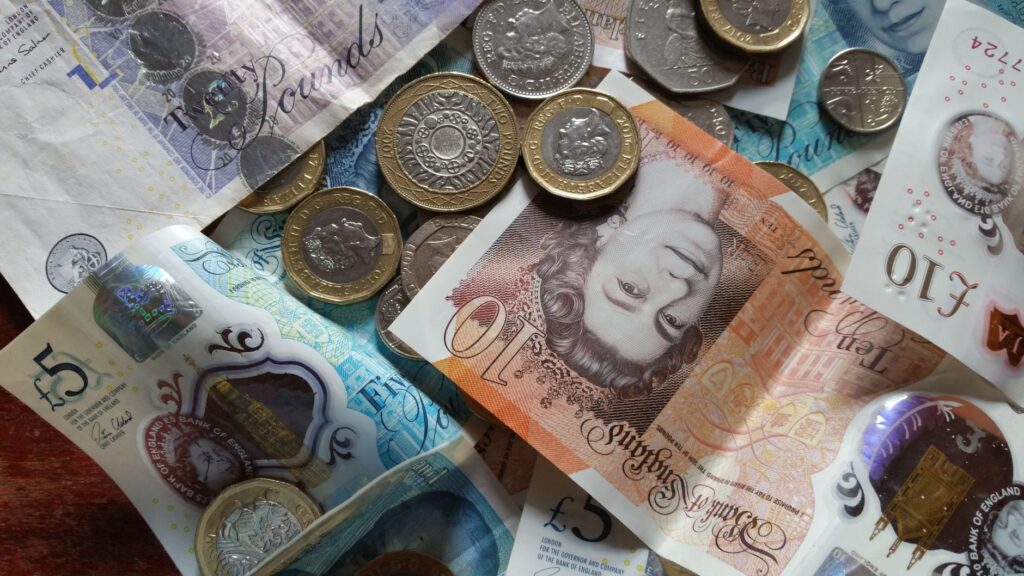 British pound banknotes and coins spread across a table