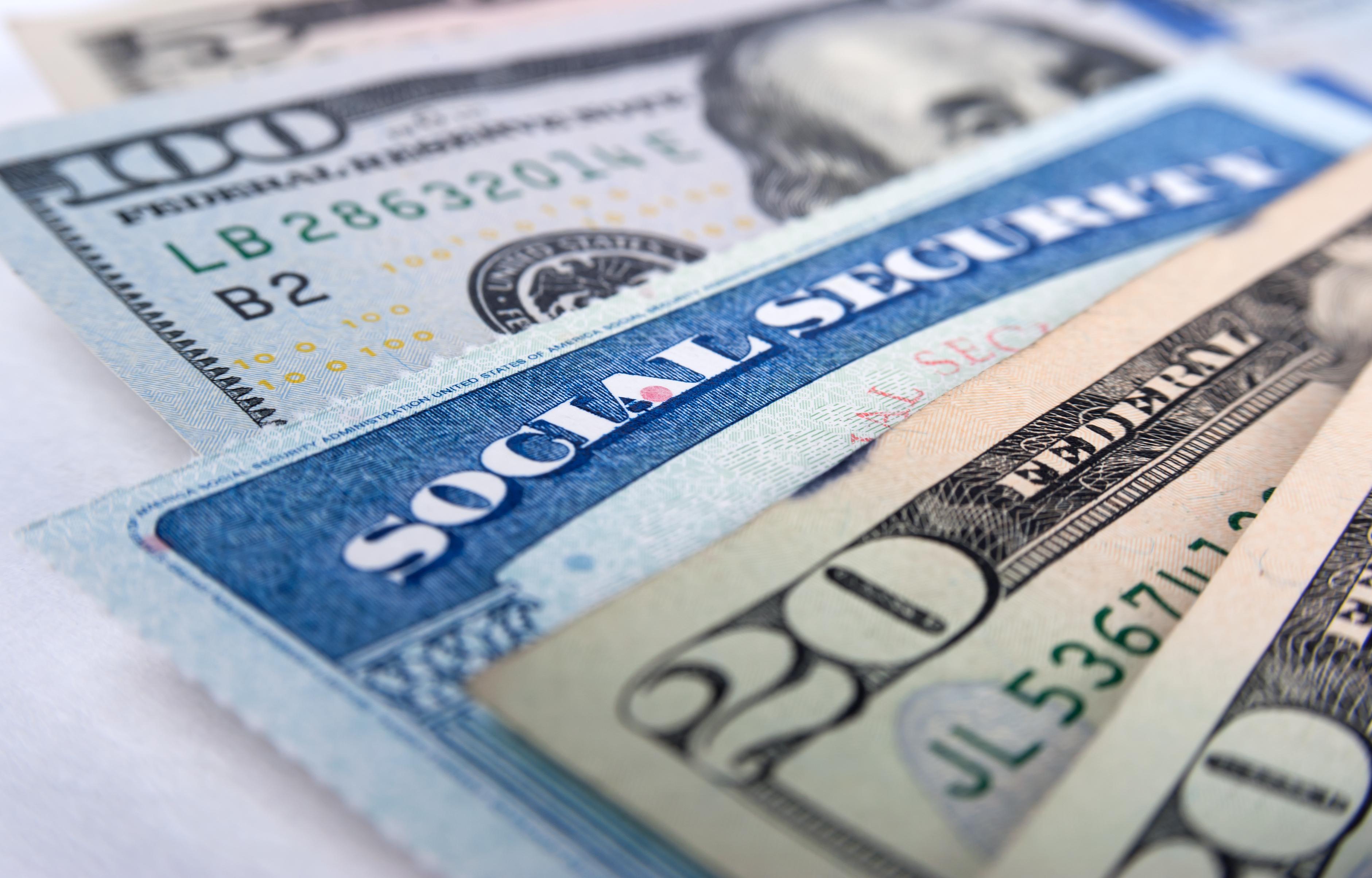 A Social Security card is wedged between a fanned assortment of cash bills.