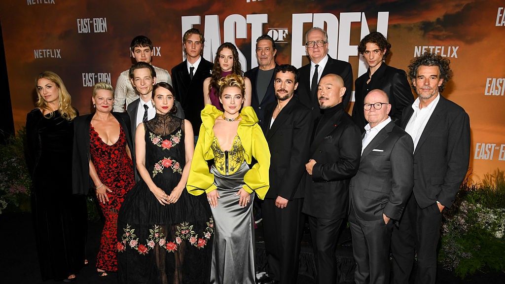 The cast of the 2026 Netflix series East of Eden poses in formalwear at a premiere carpet.