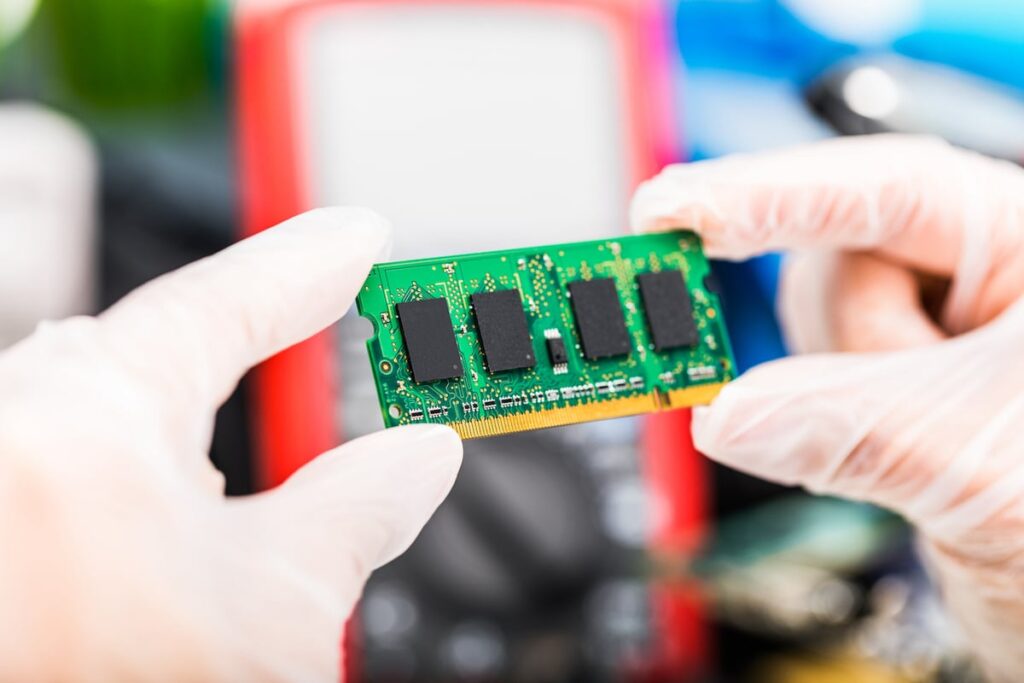 Gloved hands holding a memory chip.