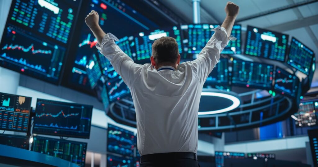 An investor cheers while looking at monitors on the trading room floor of a stock market exchange.