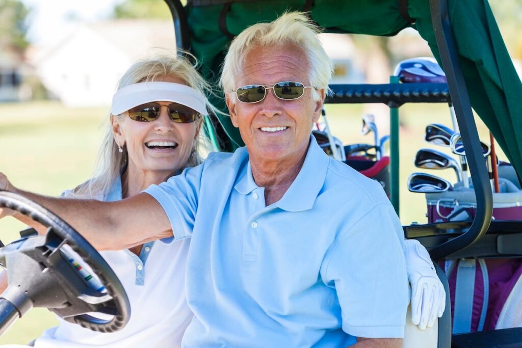 Happy senior man and woman couple together playing golf.